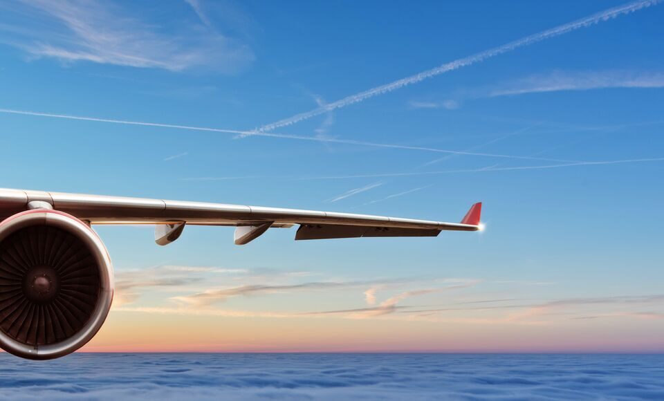 An airplane wing set against the sky, showcasing the view from above the clouds.