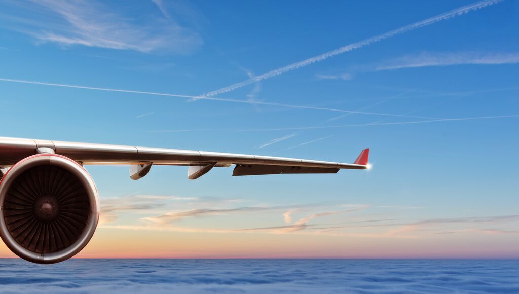 An airplane wing set against the sky, showcasing the view from above the clouds.